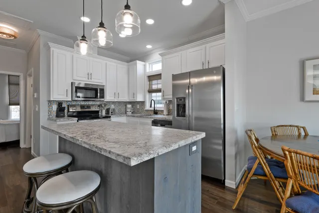 a kitchen with stainless steel appliances granite countertop a dining table chairs refrigerator and microwave