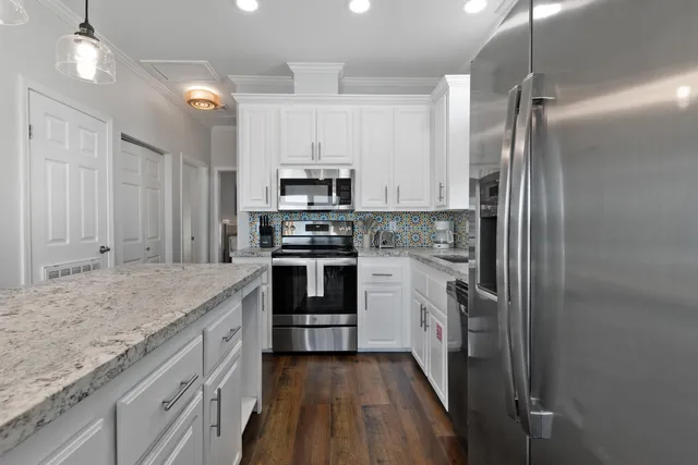a kitchen with kitchen island white cabinets and stainless steel appliances