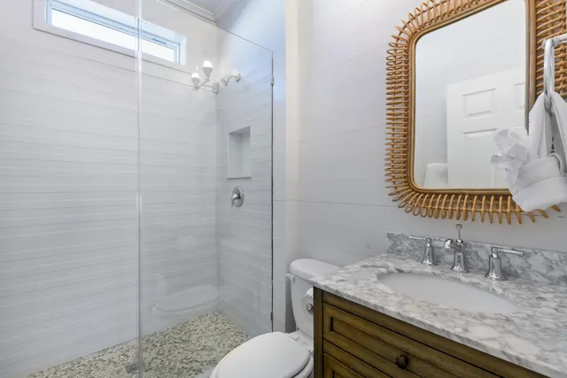 a bathroom with a granite countertop sink toilet a mirror and shower