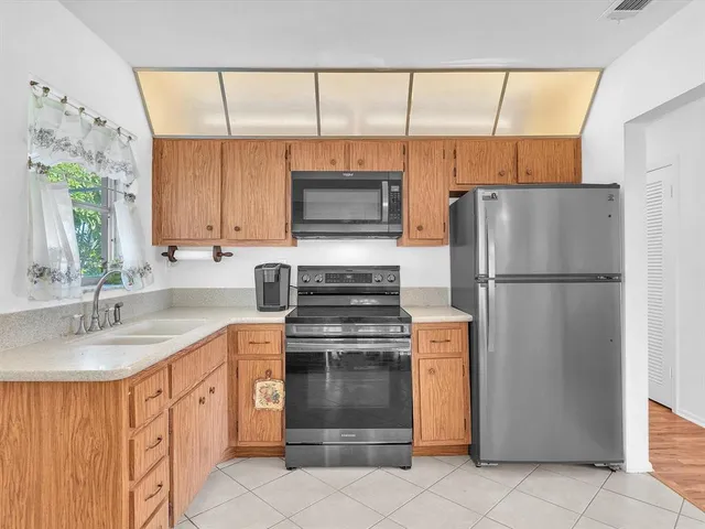 a kitchen with stainless steel appliances granite countertop a refrigerator a stove a sink and a microwave