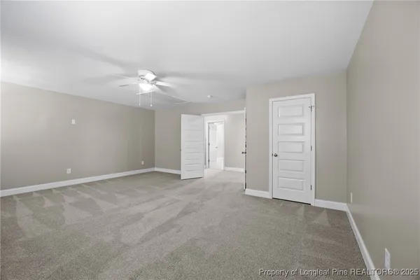an empty room with windows and ceiling fan