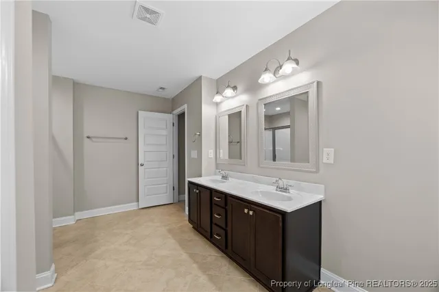 a bathroom with a granite countertop double vanity sink and mirror