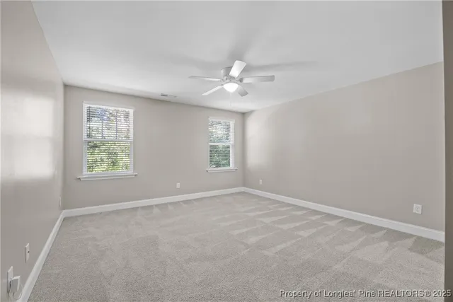 an empty room with windows and ceiling fan