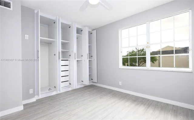 an empty room with windows closet and wooden floor