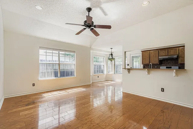 a view of empty room with wooden floor and windows