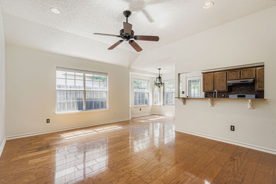 1708 Rusty Nail Loop Round Rock, TX 78681 - Photo 2 of 13 Unfurnished living room with light wood-type flooring, a textured ceiling, ceiling fan, and lofted ceiling