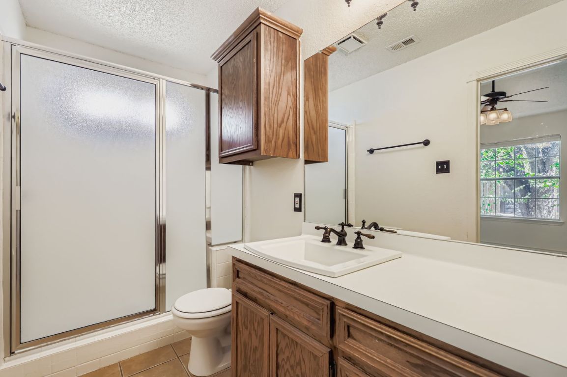 1708 Rusty Nail Loop Round Rock, TX 78681 - Photo 7 of 13 Full bath featuring light tile patterned floors, a stall shower, vanity, a textured ceiling, and ceiling fan
