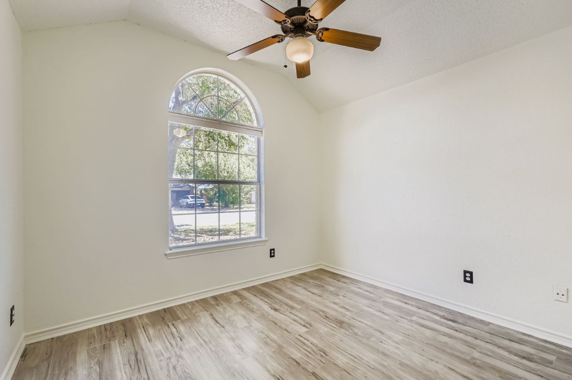 1708 Rusty Nail Loop Round Rock, TX 78681 - Photo 8 of 13 Unfurnished room featuring vaulted ceiling, light wood-style flooring, a textured ceiling, and a ceiling fan