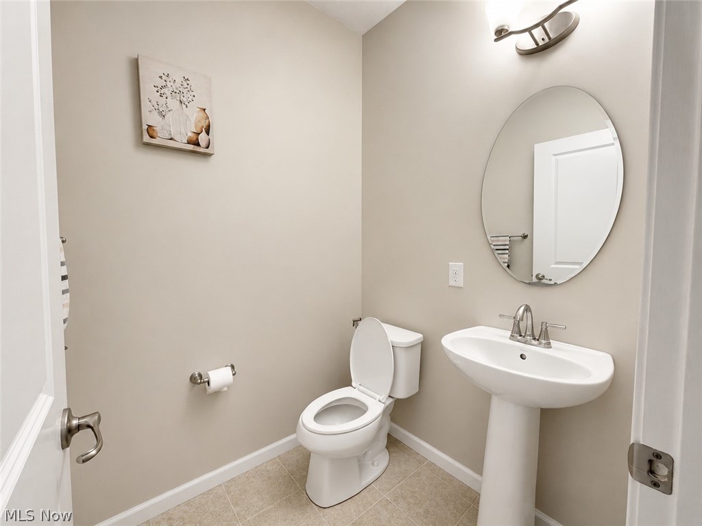 867 Starr Ridge Street Southeast Massillon, OH 44646 - Photo 12 of 29 Pedestal sink with chrome-finish faucet, oval mirror, and tile flooring