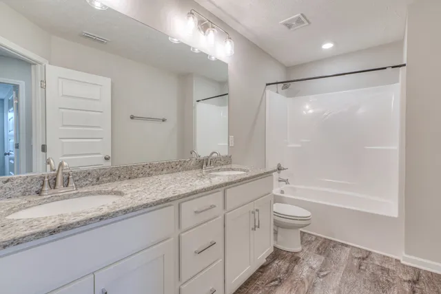 a bathroom with a granite countertop sink a toilet and bathtub