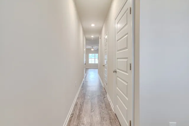 a view of a hallway with wooden floor and a bathroom