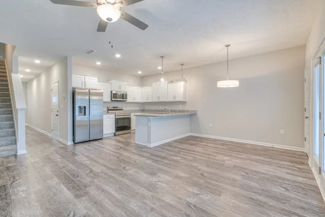 a view of kitchen with refrigerator stove and wooden floor