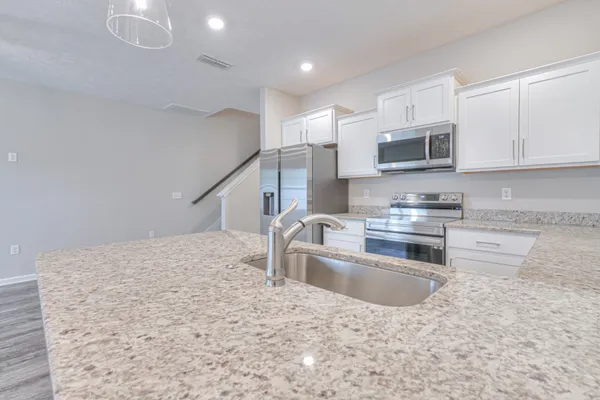 a kitchen with stainless steel appliances granite countertop a sink a stove top oven and a granite counter tops