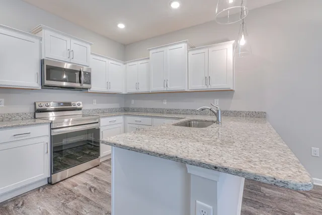 a kitchen with granite countertop a sink stainless steel appliances and white cabinets