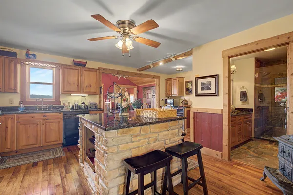 a kitchen with stainless steel appliances granite countertop a refrigerator a stove top oven a sink dishwasher and chairs with wooden floor