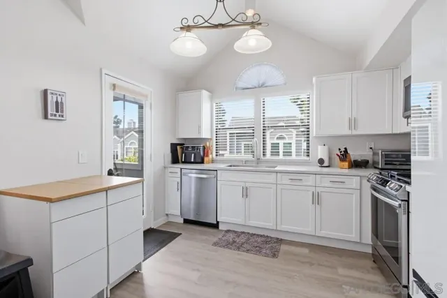 a kitchen that has a lot of white cabinets and stainless steel appliances