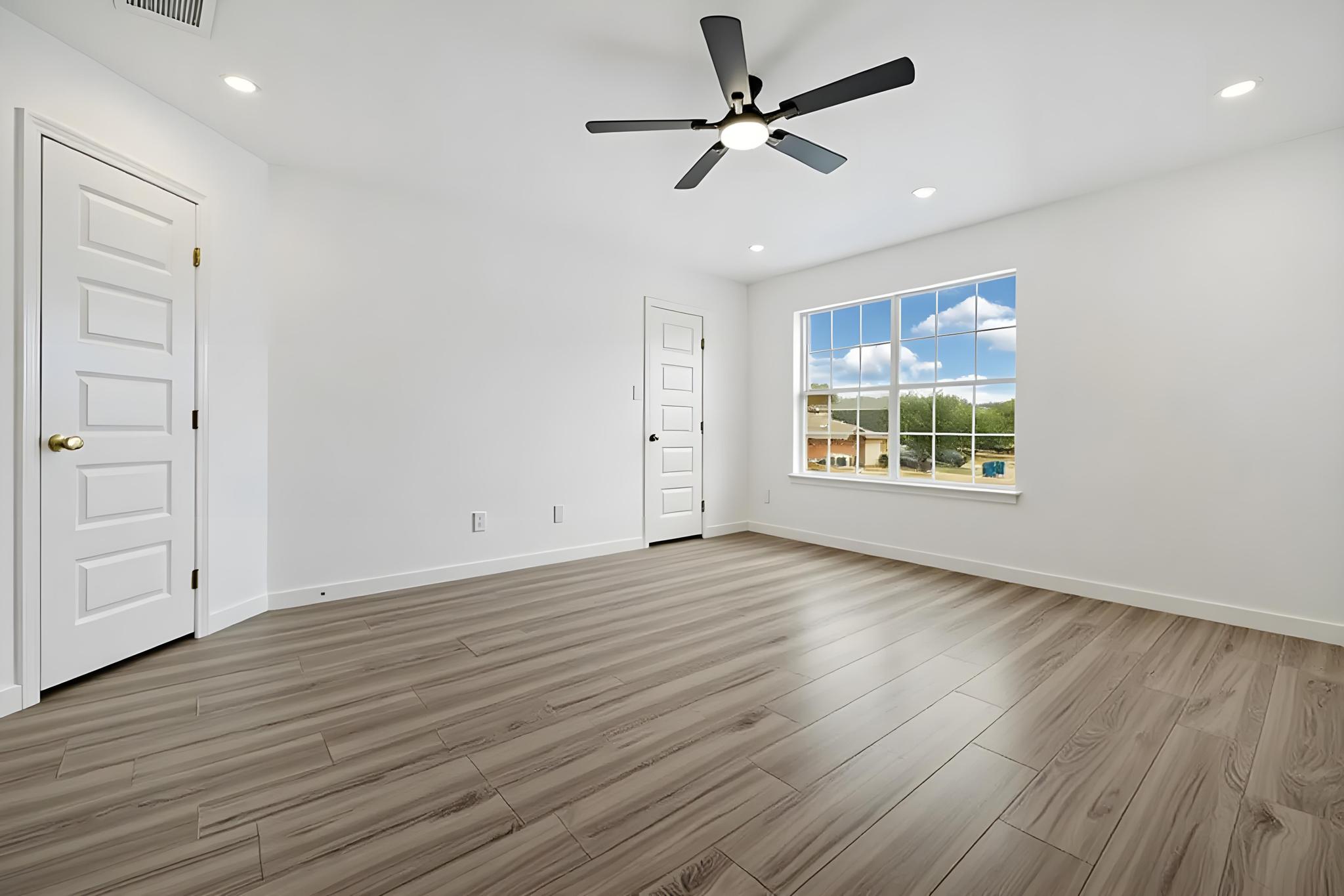 13501 Sierra Wind Lane Elgin, TX 78621 - Photo 14 of 19 Bright room featuring wood-finish flooring, a contemporary ceiling fan, recessed lighting, white baseboards, and a large window providing natural light