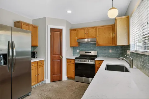 a kitchen with stainless steel appliances granite countertop a refrigerator a sink and a stove