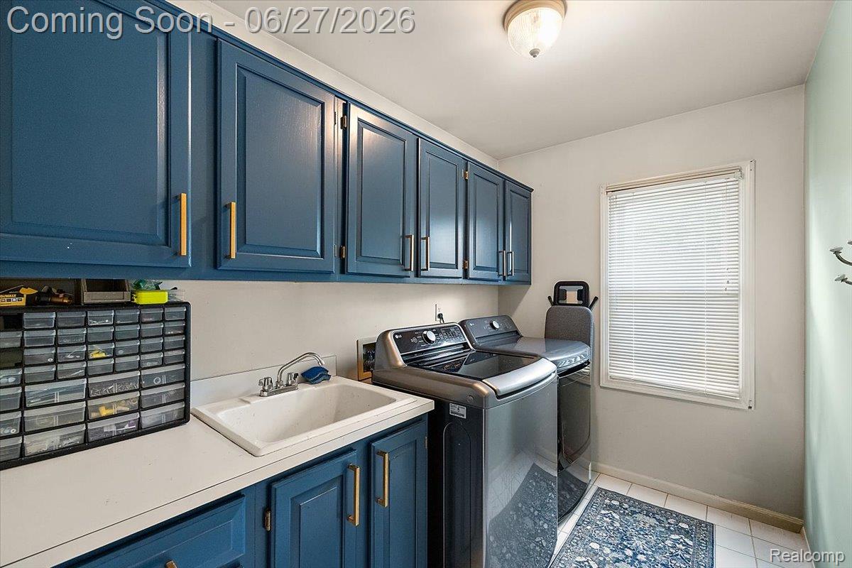 4193 Oak Tree Circle Rochester, MI 48306 - Photo 30 of 72 Dedicated laundry space featuring extensive blue cabinetry with gold hardware, a utility sink, and white countertops