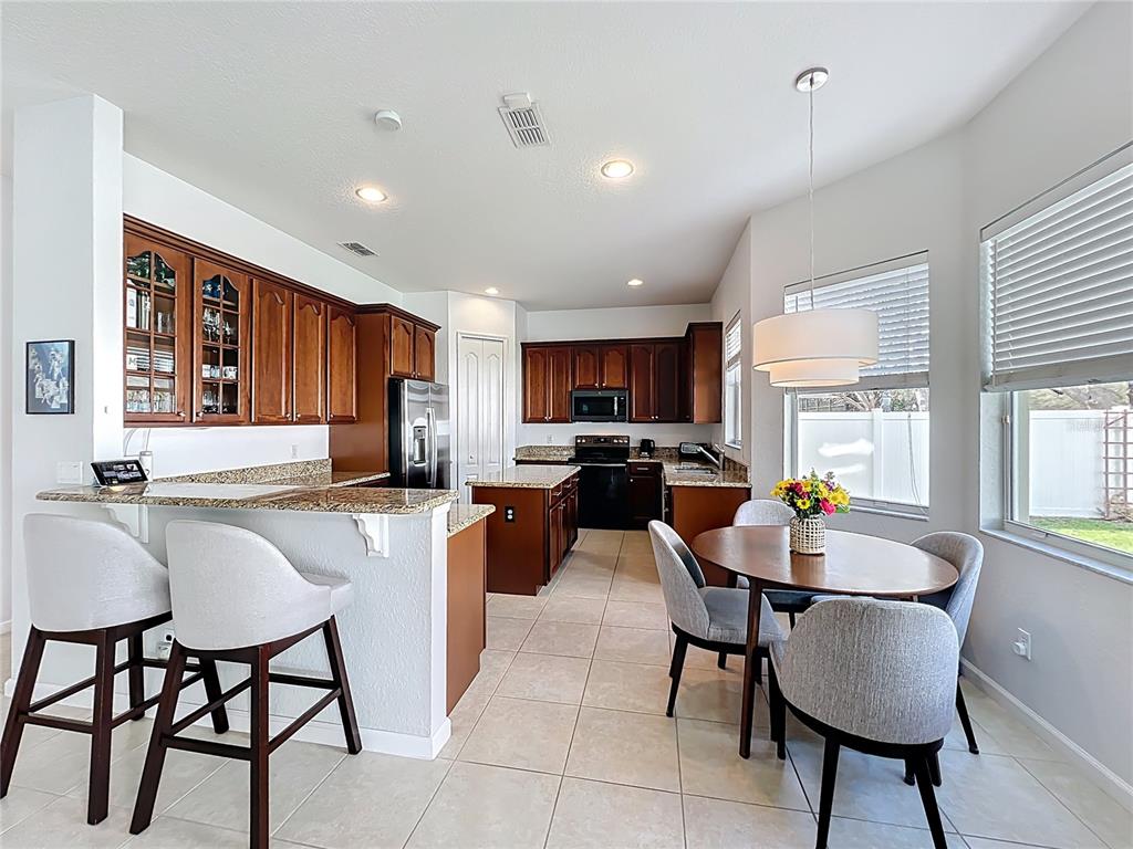 6573 Helmsley Circle Windermere, FL 34786 - Photo 18 of 54 a kitchen with stainless steel appliances granite countertop a table chairs and a refrigerator