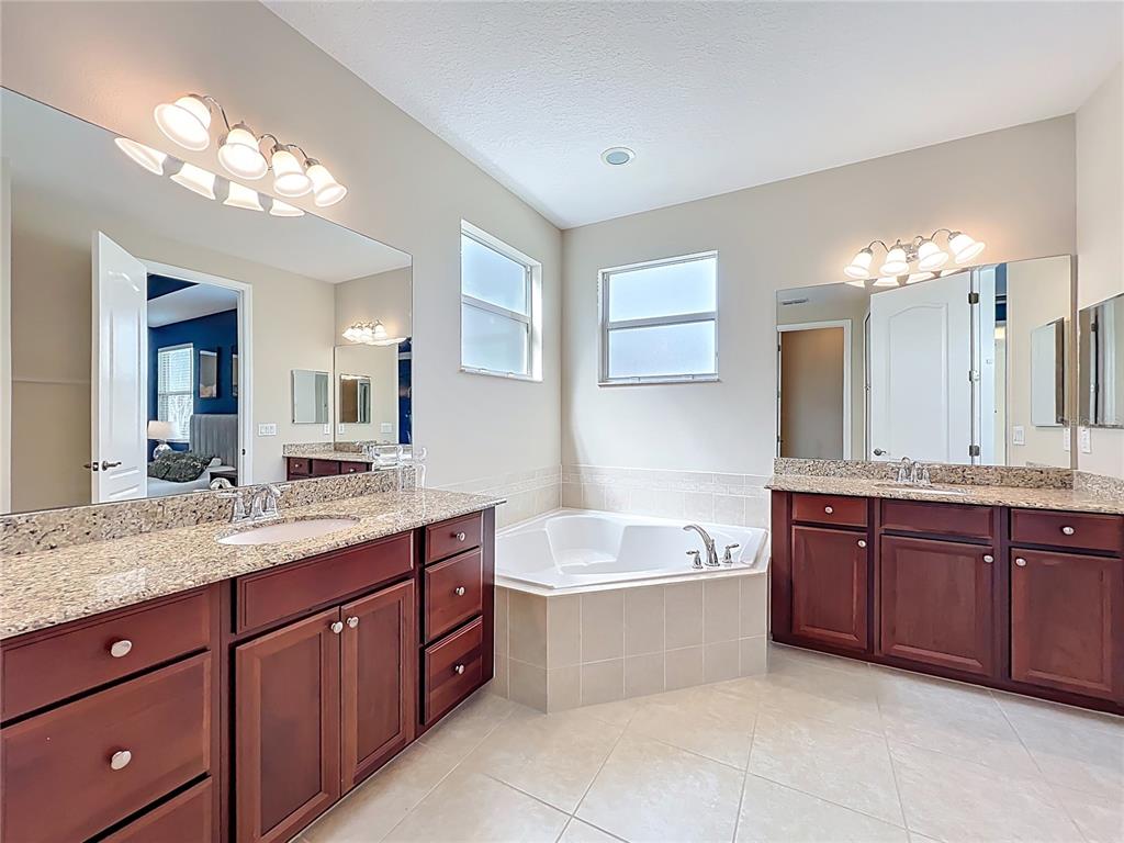 6573 Helmsley Circle Windermere, FL 34786 - Photo 39 of 54 a spacious bathroom with a granite countertop double vanity sink a bathtub a mirror and vanity