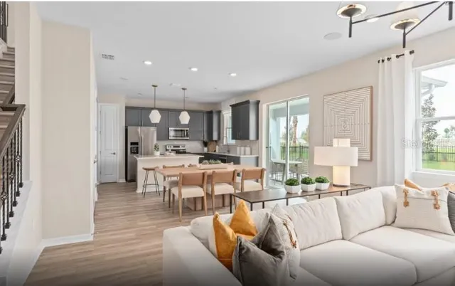 a living room with furniture kitchen and a large window