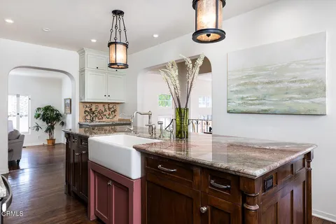 a kitchen with kitchen island granite countertop a sink appliances and cabinets