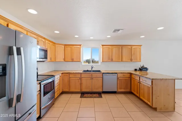 a kitchen with granite countertop a refrigerator and a stove top oven