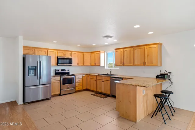 a kitchen with granite countertop a refrigerator and a stove top oven