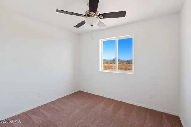 an empty room with a window and a fan