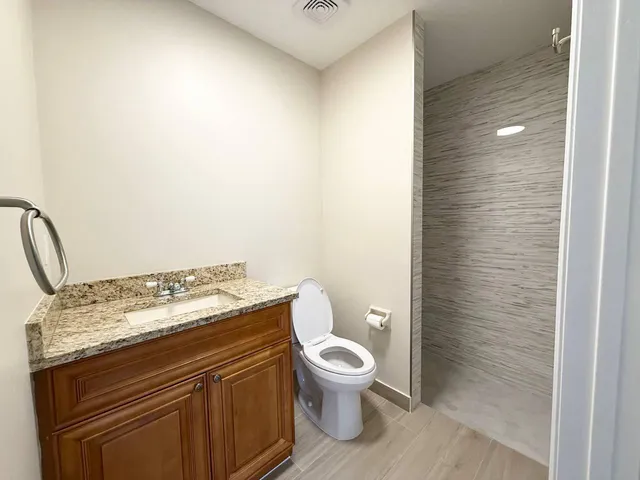 a bathroom with a granite countertop toilet and a sink