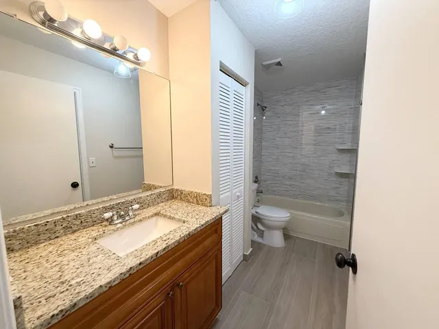 a bathroom with a granite countertop sink toilet and shower