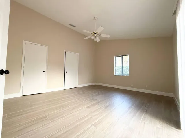 an empty room with wooden floor and windows
