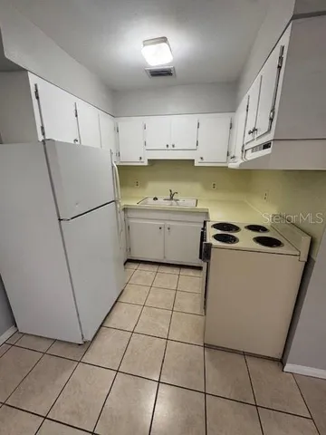 a kitchen with a refrigerator a stove top oven and cabinets