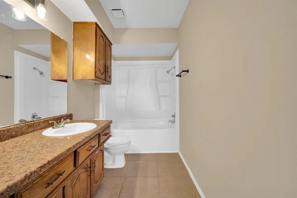 a bathroom with a granite countertop sink a toilet a mirror and bathtub
