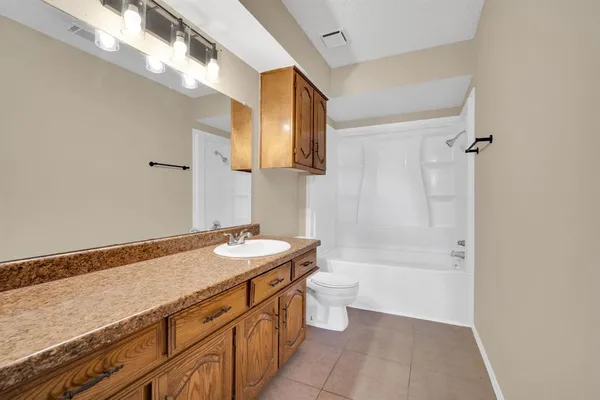a bathroom with a granite countertop sink a toilet and shower