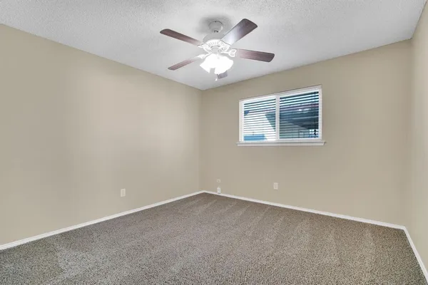 an empty room with a chandelier fan and windows