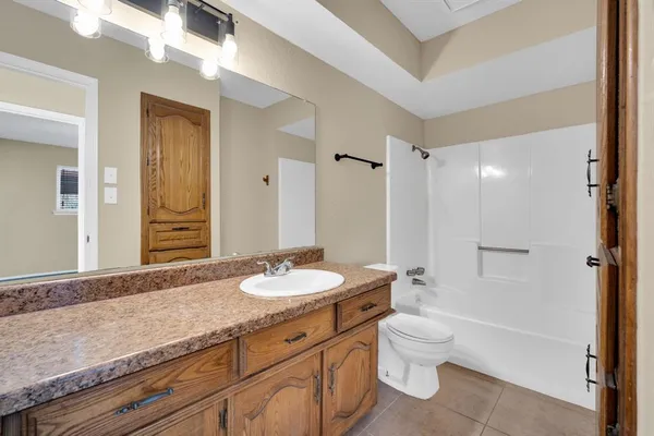 a bathroom with a granite countertop sink toilet mirror and shower