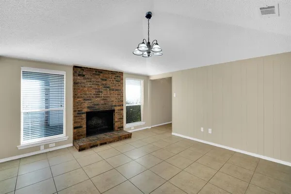 an empty room with windows and fireplace