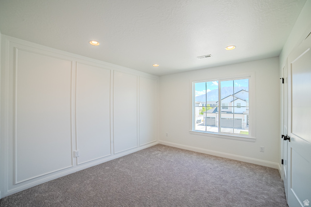 45 North Scarlet Maple Road, Unit 4317 Vineyard, UT 84059 - Photo 23 of 35 Carpeted interior room featuring a window with grid panes, recessed ceiling lighting, a paneled accent wall, and a white interior door with dark hardware