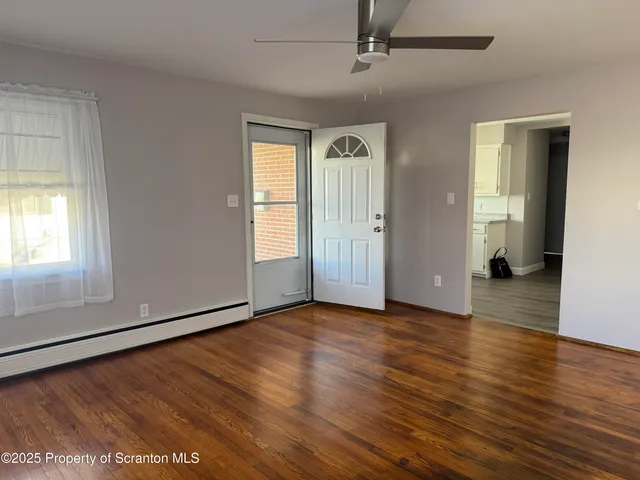 an empty room with wooden floor and windows