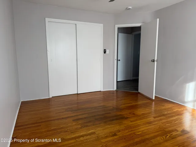 a view of an empty room with wooden floor and closet