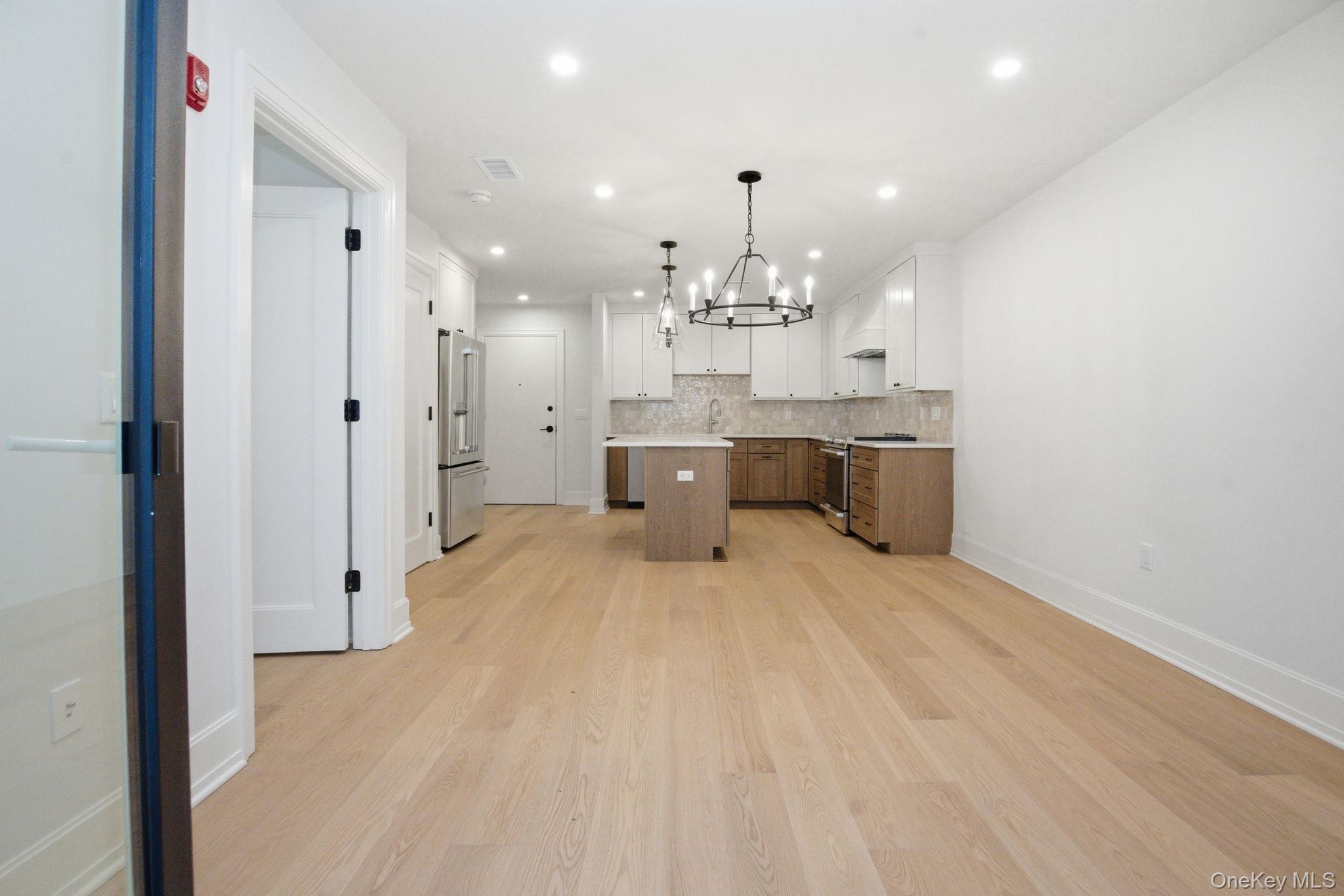 25 South Riverside Avenue, Unit 107 Croton-on-Hudson, NY 10520 - Photo 11 of 42 a large white kitchen with kitchen island a sink stainless steel appliances and cabinets