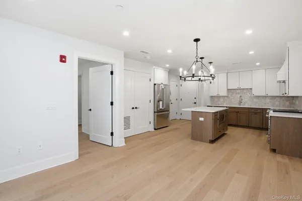 a large white kitchen with a refrigerator a sink dishwasher a stove and a dining table with wooden floor
