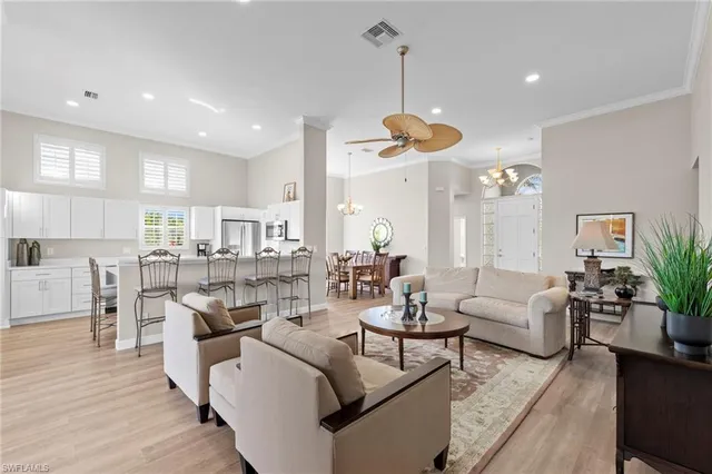 a living room with furniture kitchen view and a chandelier