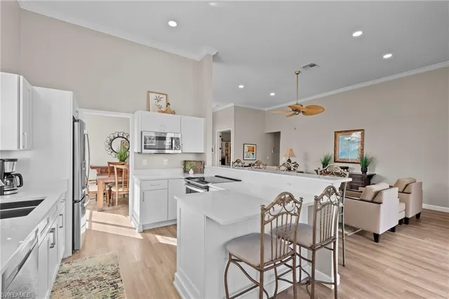 a kitchen with stainless steel appliances granite countertop a refrigerator a stove a sink a dining table and chairs with wooden floor