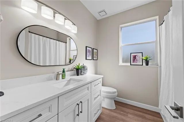 a bathroom with a granite countertop toilet sink and mirror