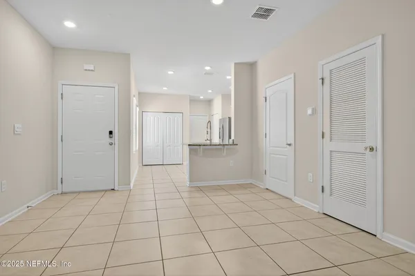 an empty room with kitchen and chandelier fan