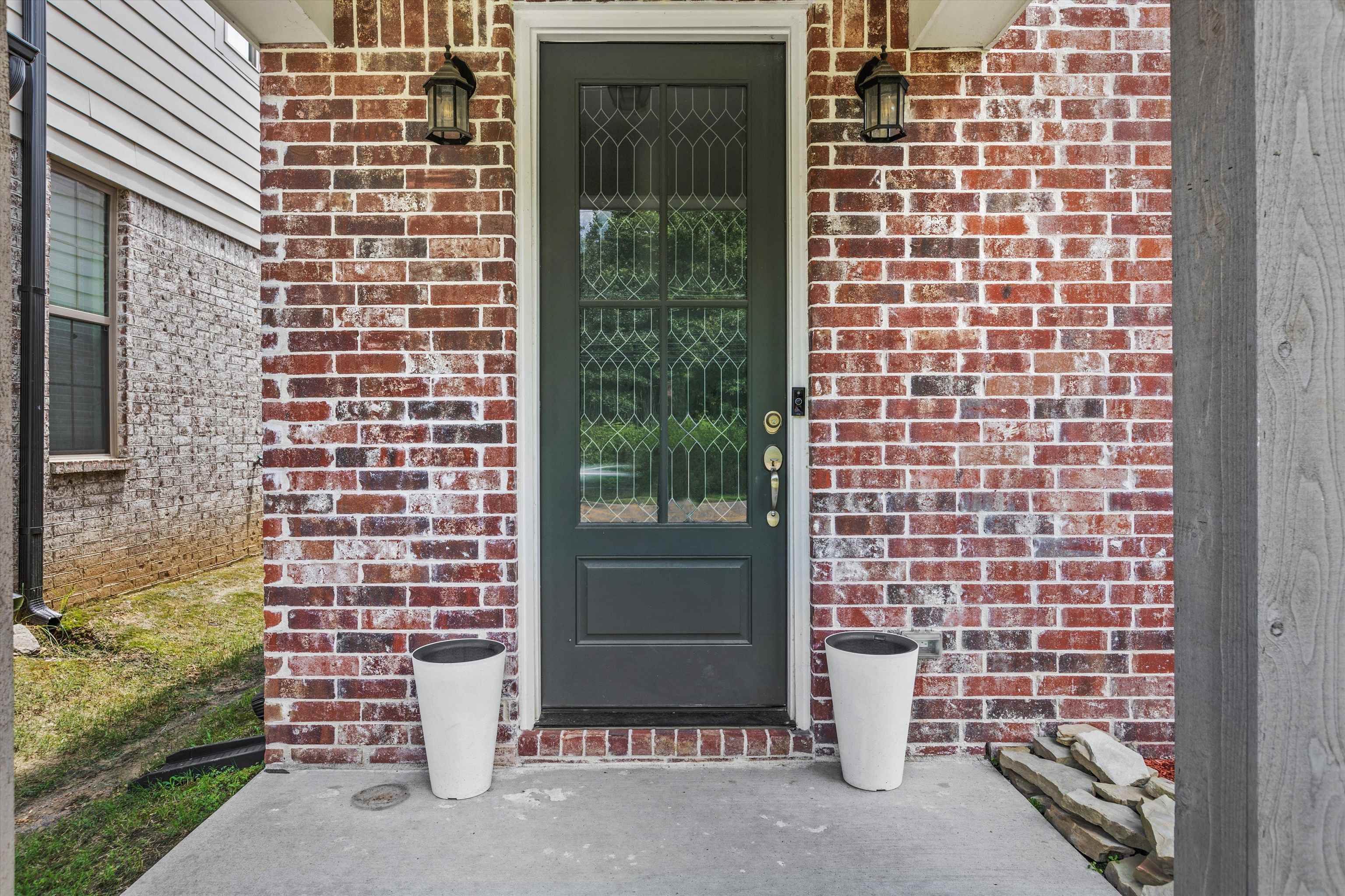10139 Macon Road Cordova, TN 38018 - Photo 4 of 31 Front entry featuring a leaded glass door, brick facade, wall sconces, concrete porch, and vertical wood siding