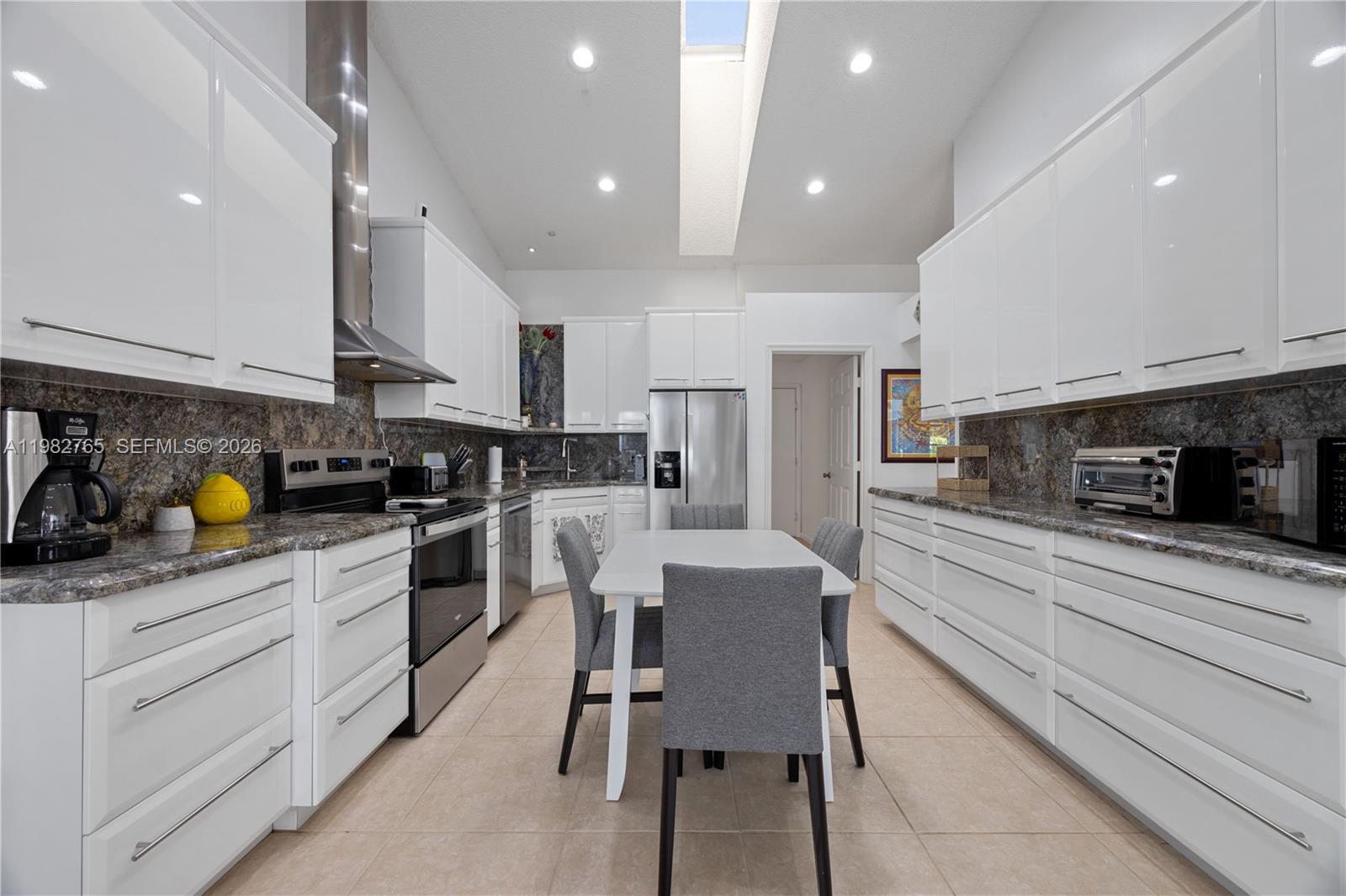 8962 Southeast Riverfront Terrace Jupiter, FL 33469 - Photo 3 of 20 a kitchen with stainless steel appliances kitchen island granite countertop a table chairs microwave and cabinets
